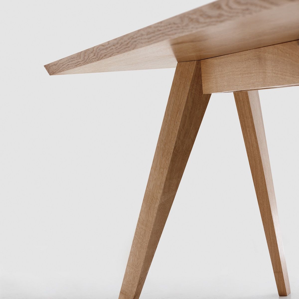 Detailaufnahme des CENA Tisches: Rechteckiger Esstisch aus hellem Holz mit schrägen Beinen und minimalistischem Design.