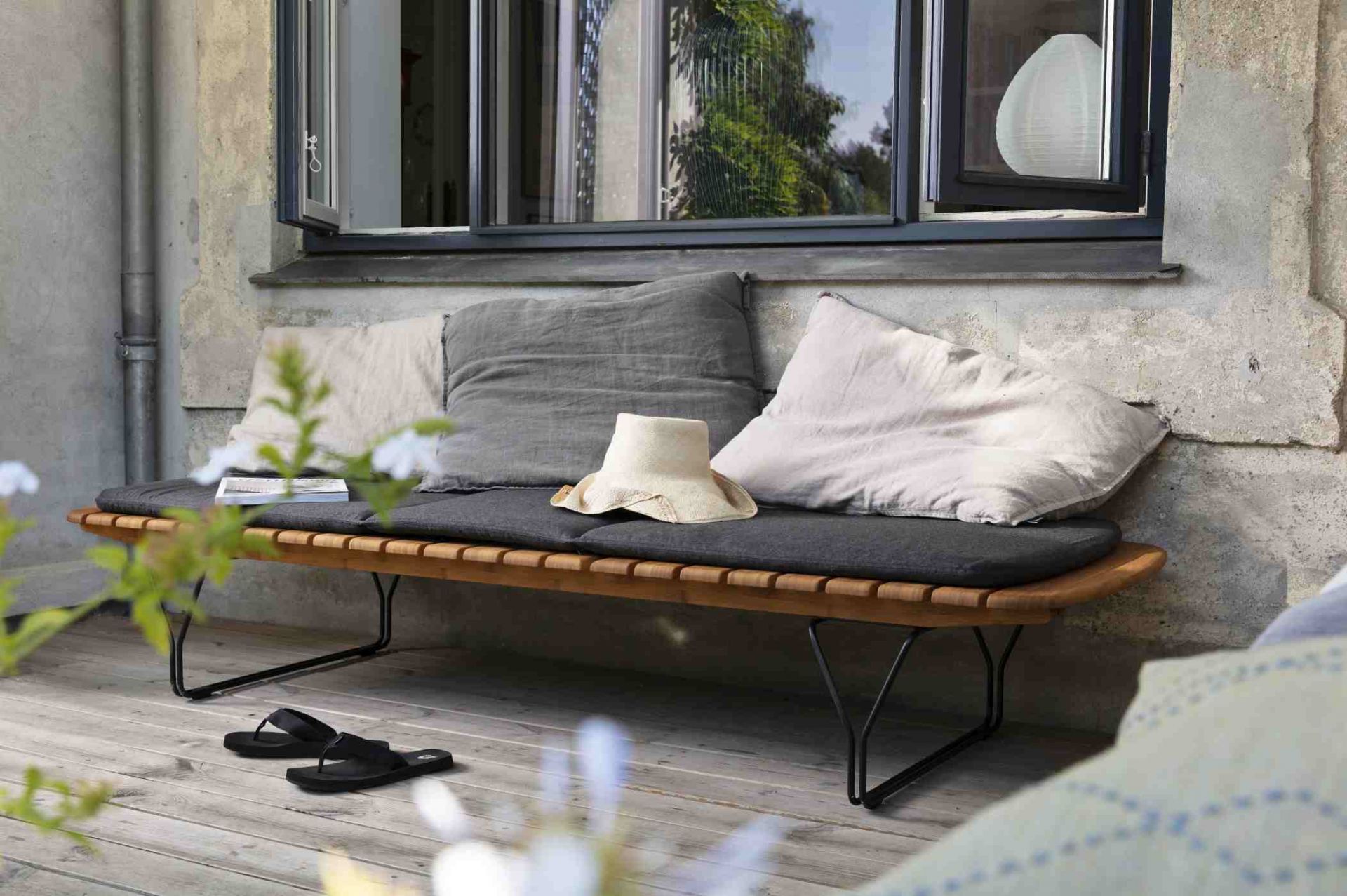 Molo Outdoor Cushion Kissen für Houe Sonnenliege, graue Sitzauflage und Dekokissen auf Holzbank.