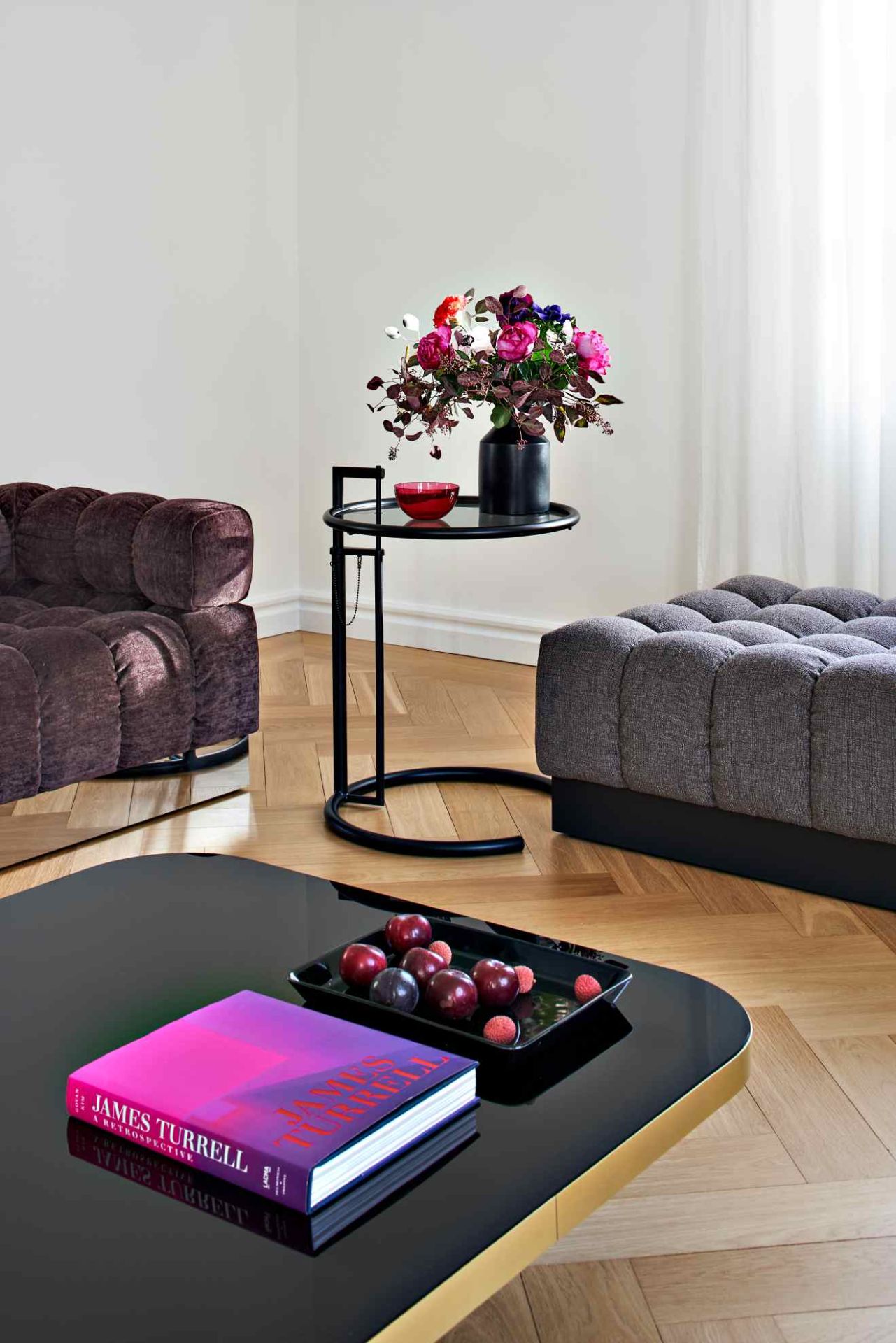 ClassiCon Bow Coffee Table No. 4: Schwarzer Couchtisch mit Buch und Obst, modernes Wohnzimmer-Interieur.