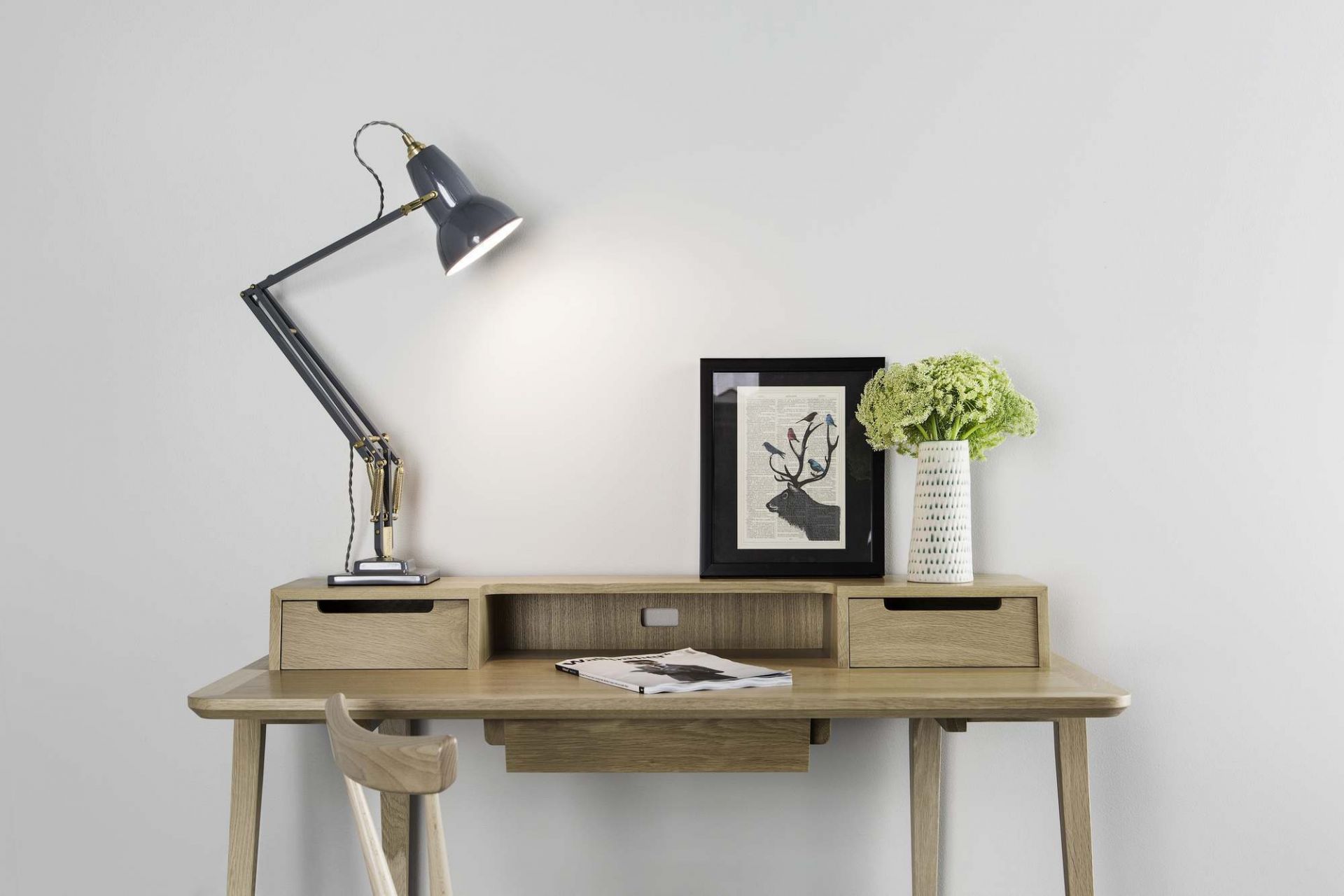 Anglepoise Original 1227 Brass Tischleuchte in Grau auf einem Holzschreibtisch mit Dekoration und Stuhl.