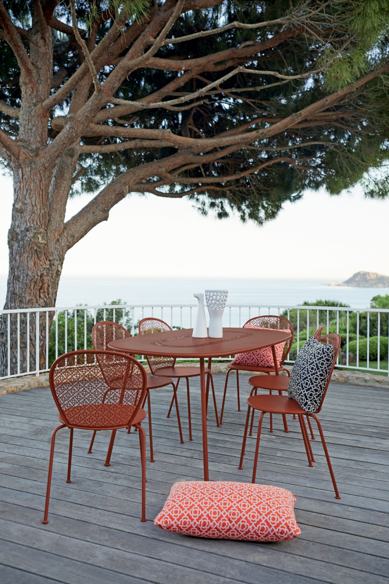 Fermob Lorette Stühle und Tisch in Rotbraun auf Holzterrasse mit Meerblick, Outdoor Möbel.