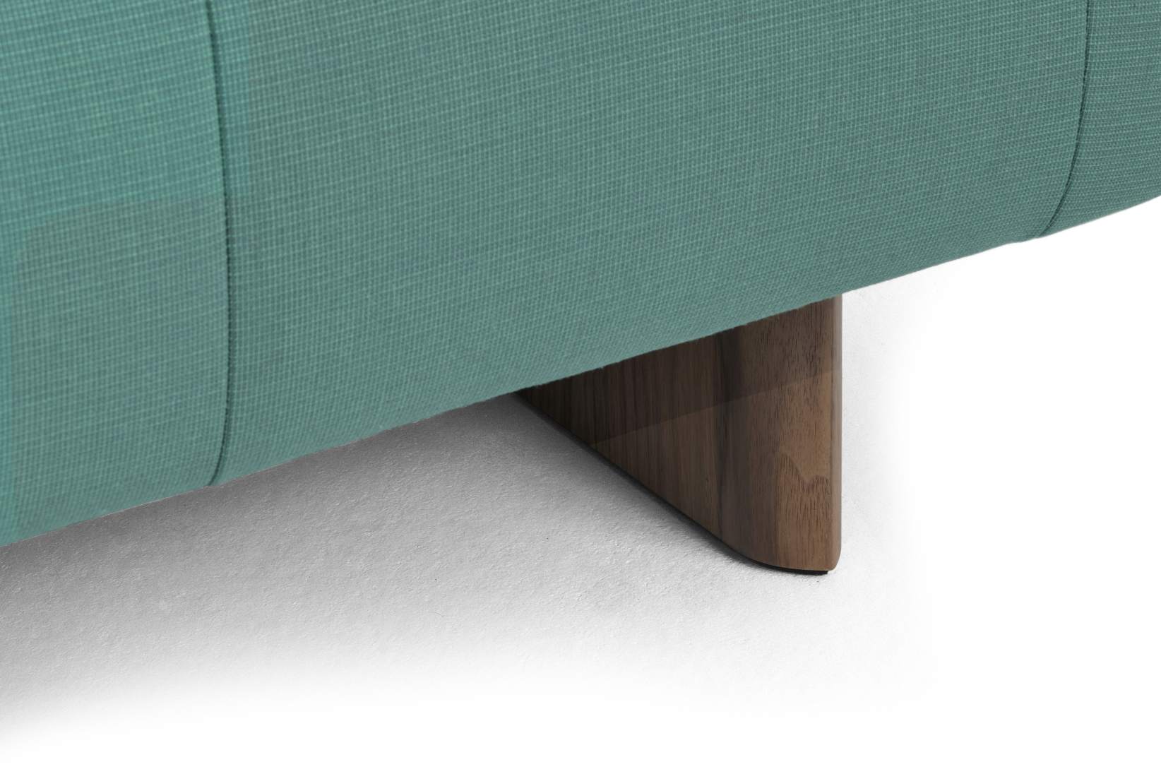 Detailaufnahme vom Quilton Sofa von Hay, petrolfarbener Stoffbezug und dunkles Holzbein.