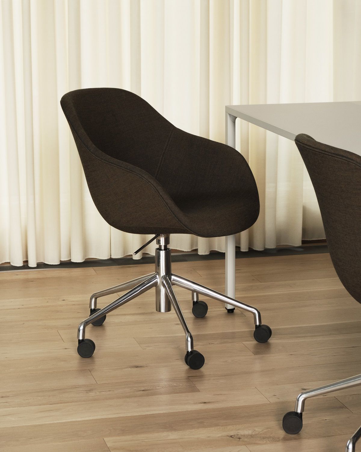 Brauner About a Chair AAC155 Soft Duo Bürostuhl von Hay mit Rollen vor Vorhang.
