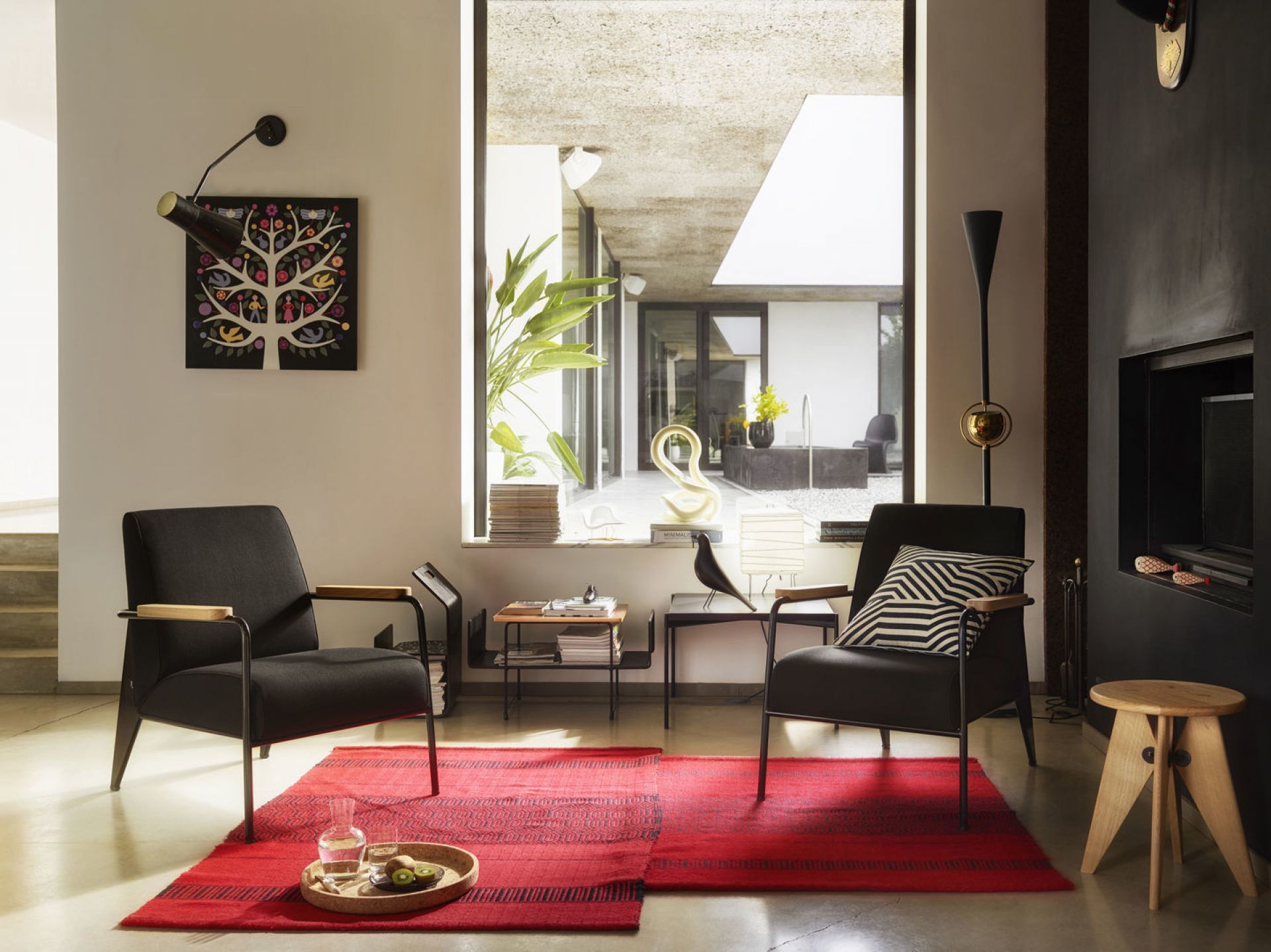 Schwarzer Fauteuil De Salon Sessel von Vitra im modernen Wohnzimmer mit rotem Teppich und Designelementen.