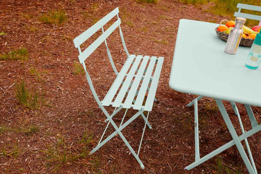 Hellblaue Fermob Bistro Klappbank und Tisch im Garten, Outdoor-Möbel für zwei Personen.