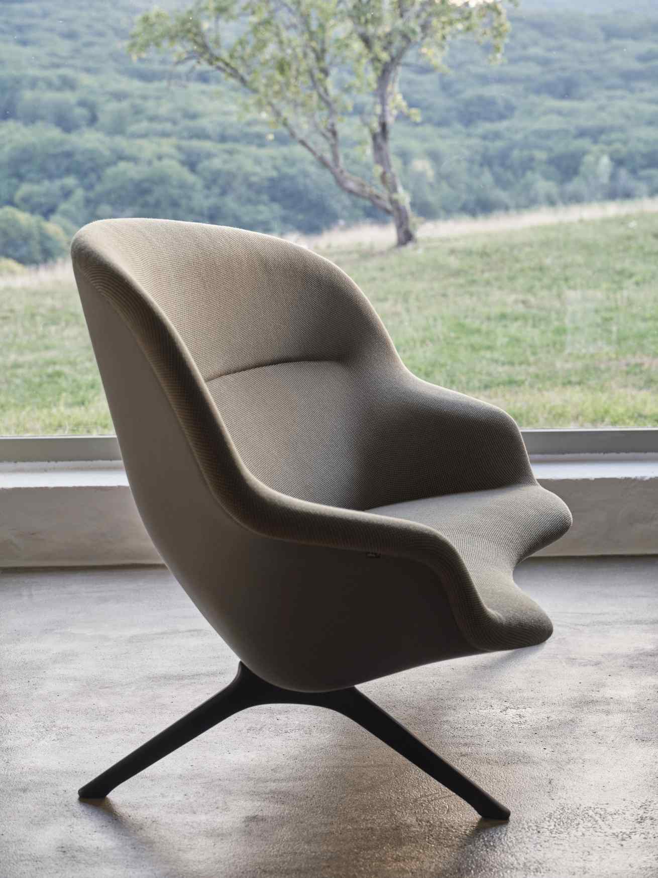 Vitra Abalon Sessel mit Stoffbezug und schwarzem Fußkreuz vor Fenster mit Landschaft.