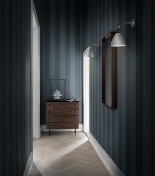 Gubi Kommode 62 Dresser aus dunklem Holz mit vier Schubladen im Flur mit Tapete.
