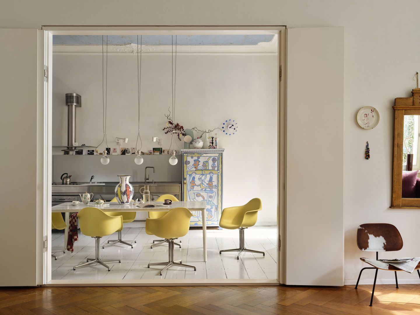Gelbe Eames Plastic Arm Chairs DAL mit Sitzpolster von Vitra um einen Esstisch in Küche.