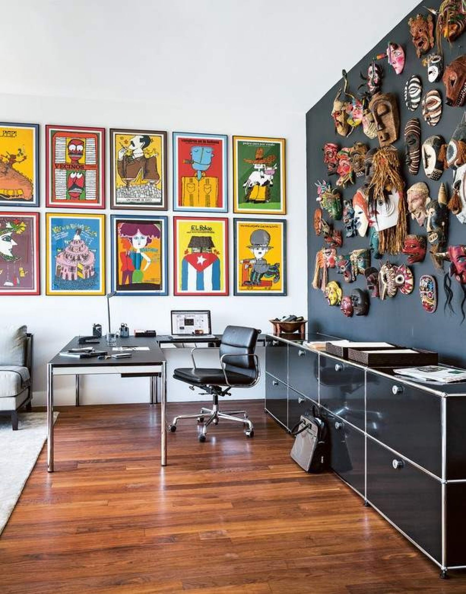 Schwarzer USM Haller Tisch 150x75 im modernen Büro mit Kunst und Masken an der Wand.