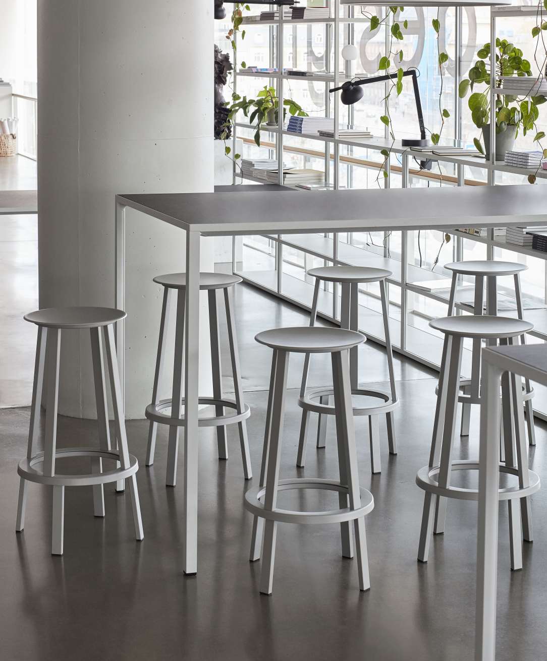 Graue Revolver Bar Stools Barhocker High Hay um einen hohen Tisch in modernem Interieur.