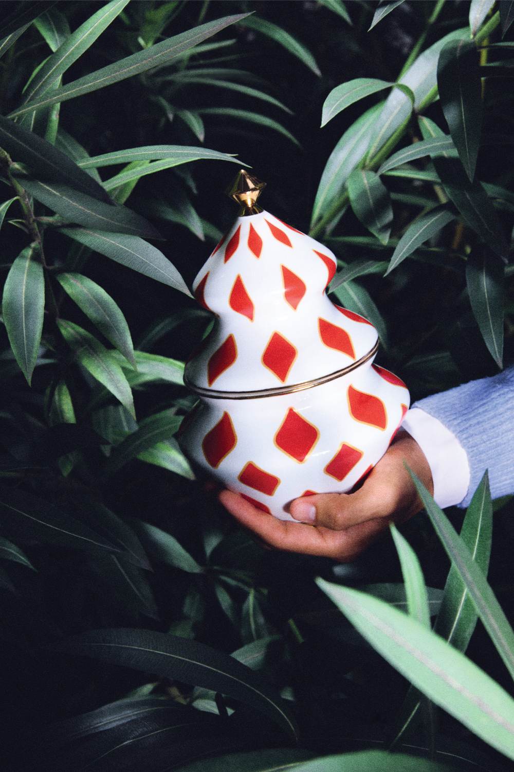 Alessi Delight Süßigkeitenbehälter NZ03 in Hand, weiß mit roten Rauten, goldener Deckel.