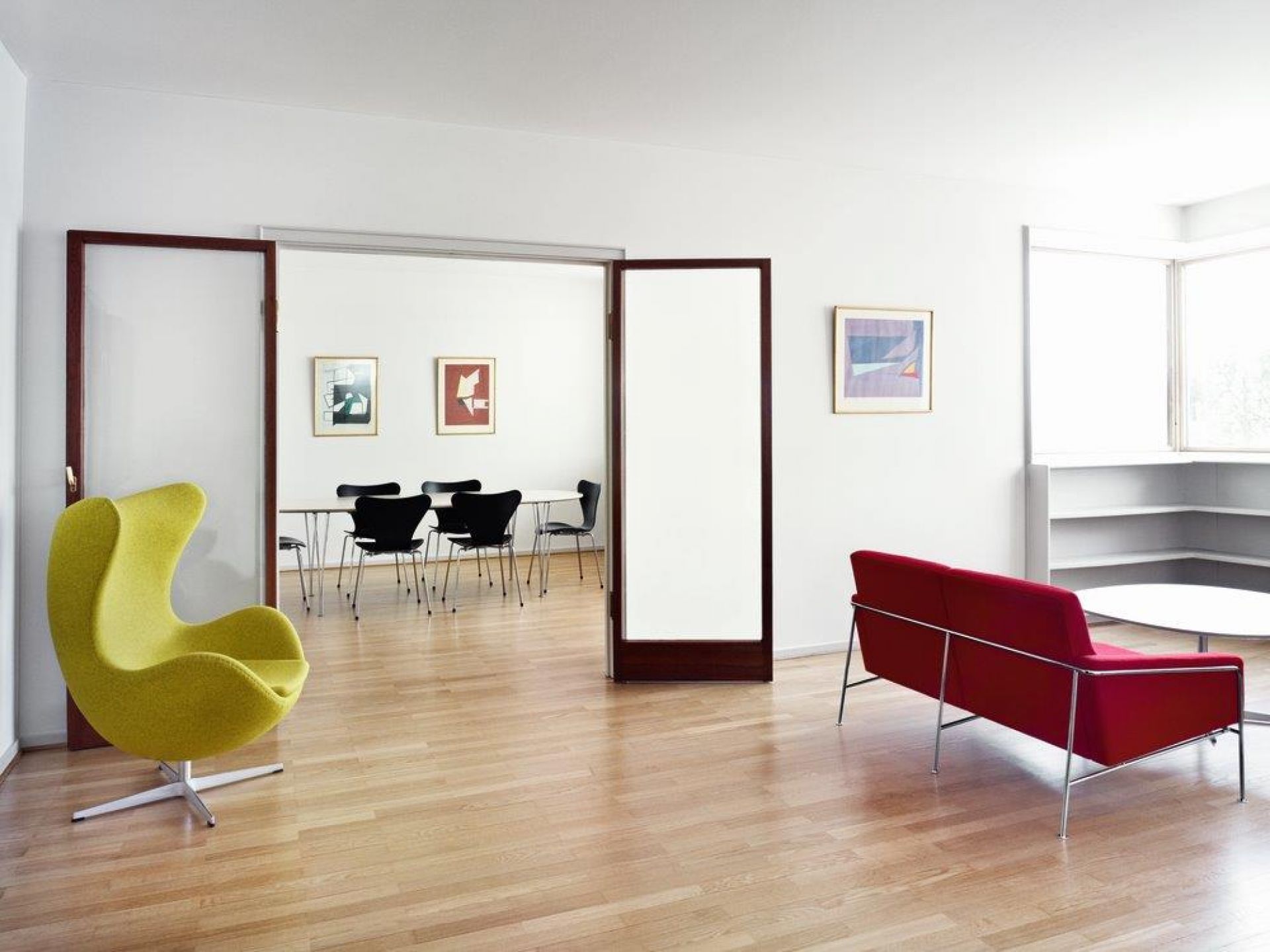 Gelber Egg Chair Sessel von Fritz Hansen in modernem Wohnzimmer mit rotem Sofa und Esstisch.