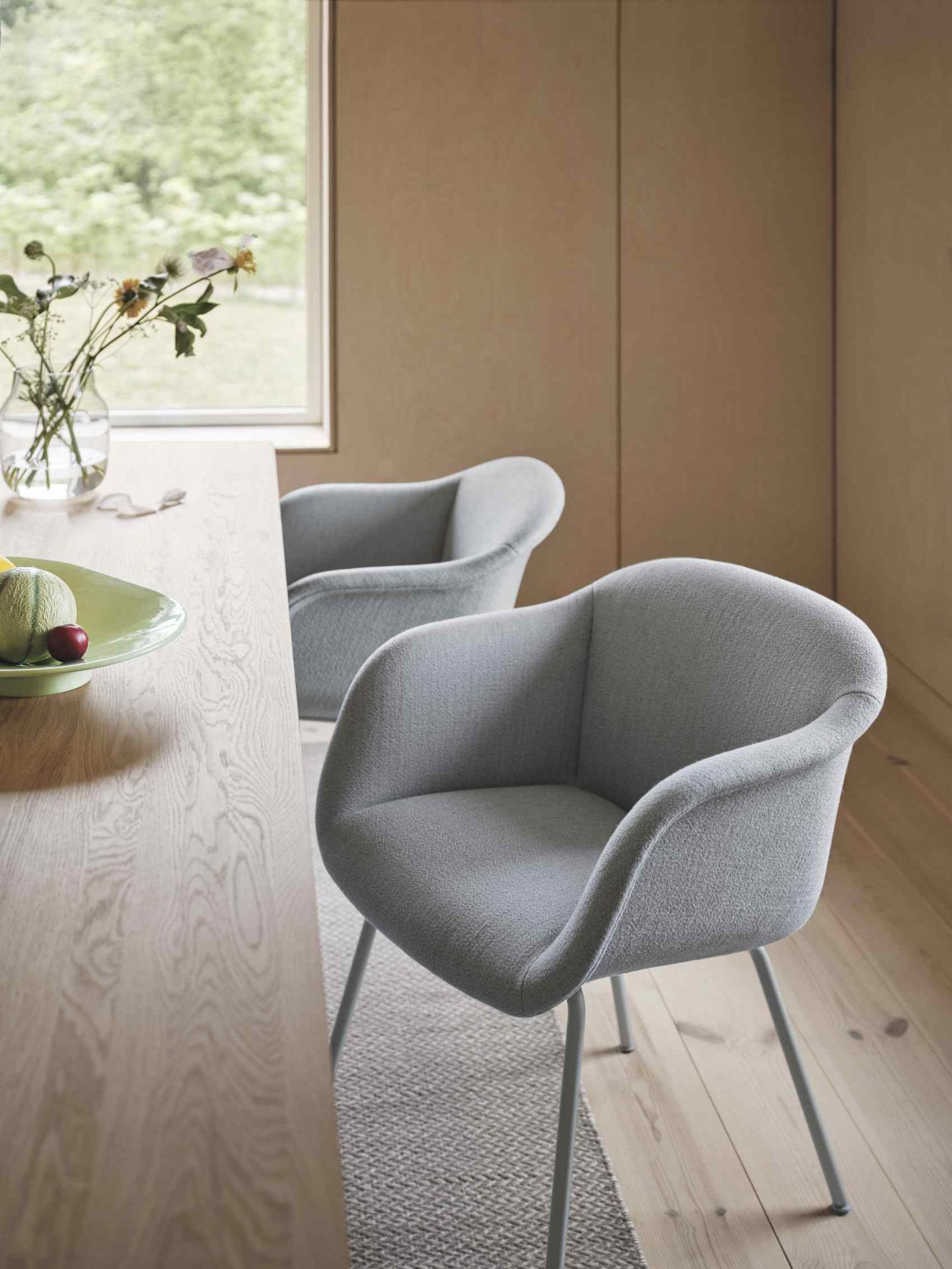 Heller Raum mit zwei grauen Fiber Soft Armlehnstühlen von Muuto am Holztisch mit Dekoration.