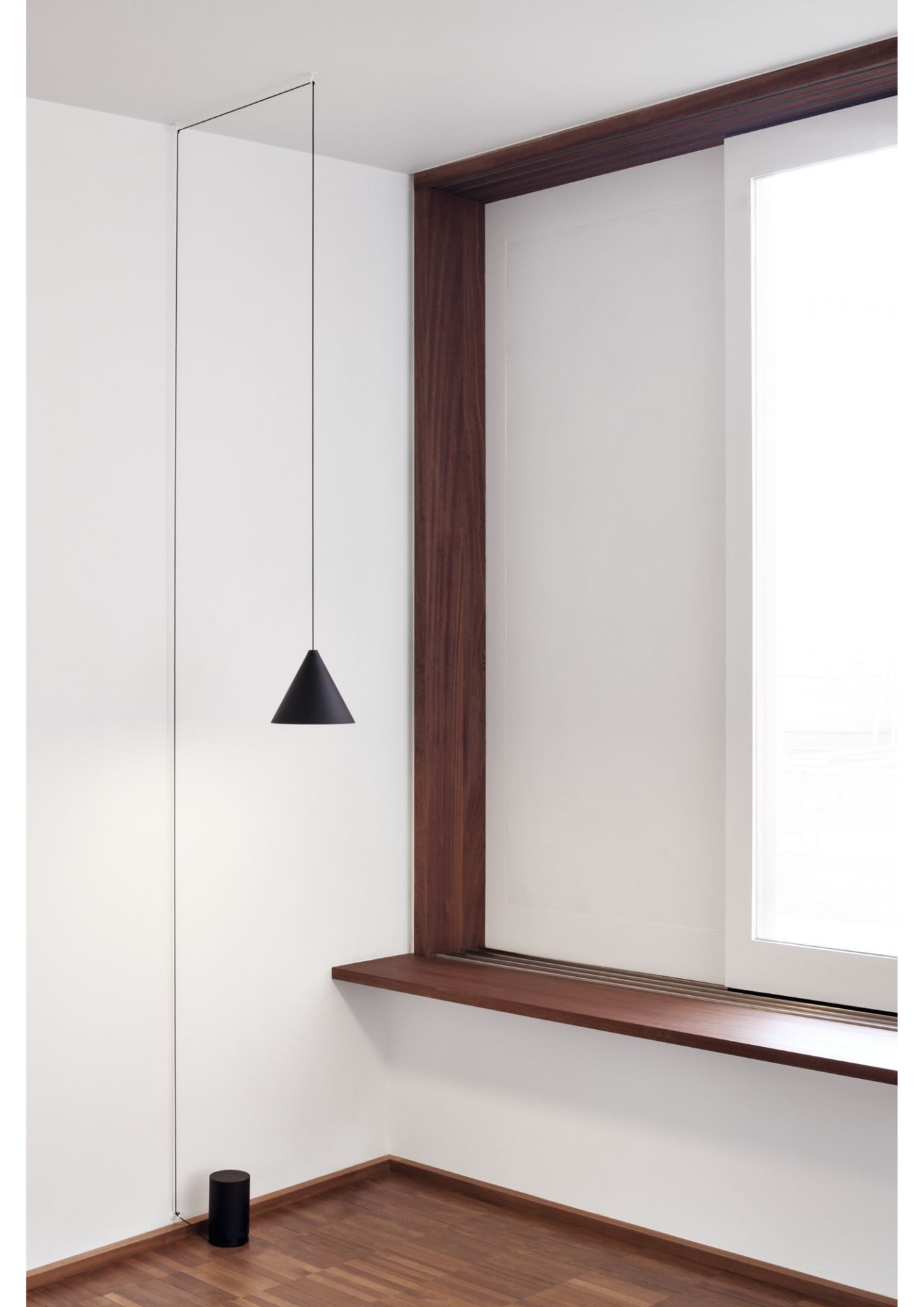 Schwarze String Light Cone Pendelleuchte von Flos in minimalistischem Raum mit Holzdetails und Fenster.