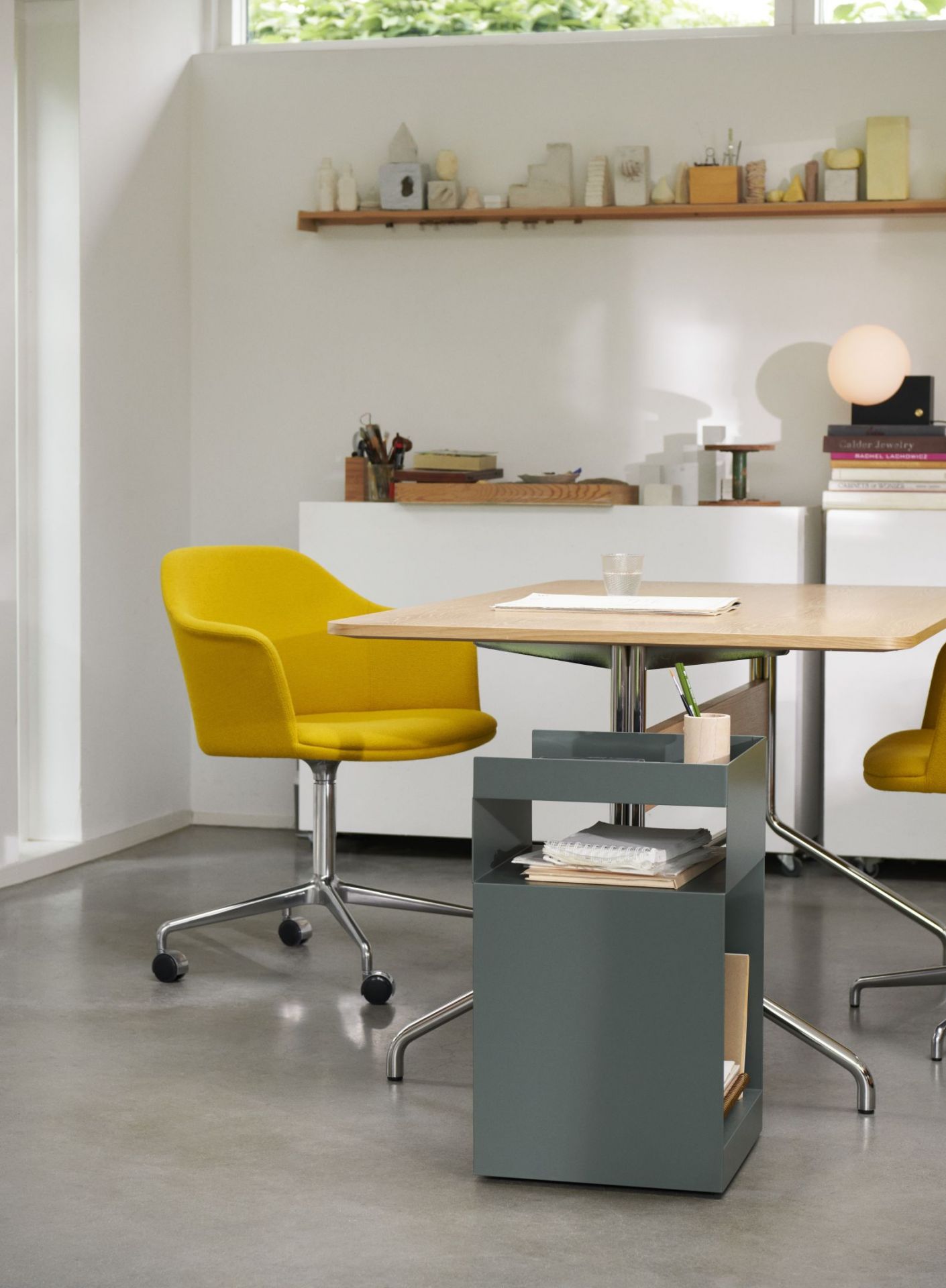 Pavilion AV18 Tisch von AndTradition mit gelbem Bürostuhl und grauem Rollcontainer in modernem Büro.