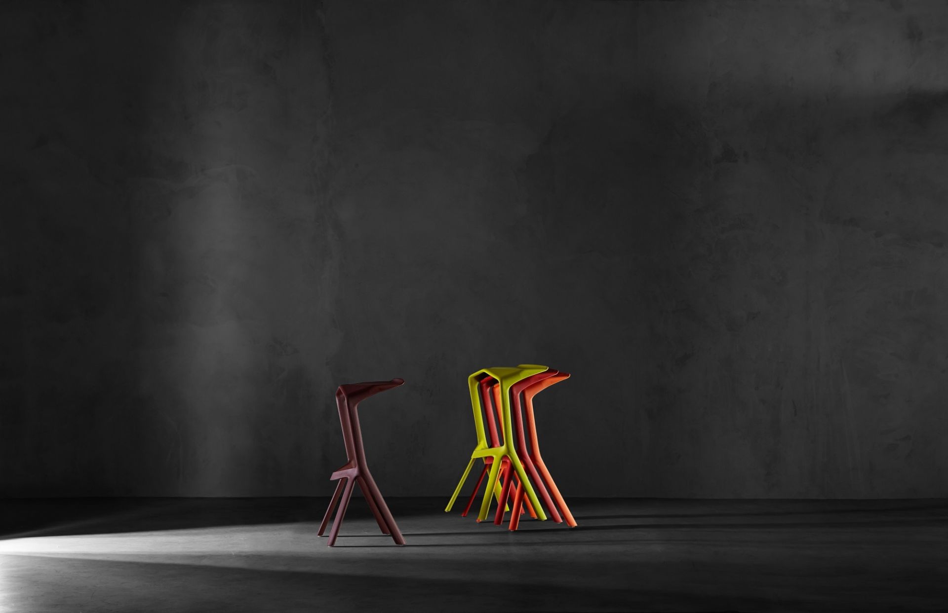 Miura Barhocker von Plank, stapelbar, in verschiedenen Farben vor dunklem Hintergrund. Design Hocker.