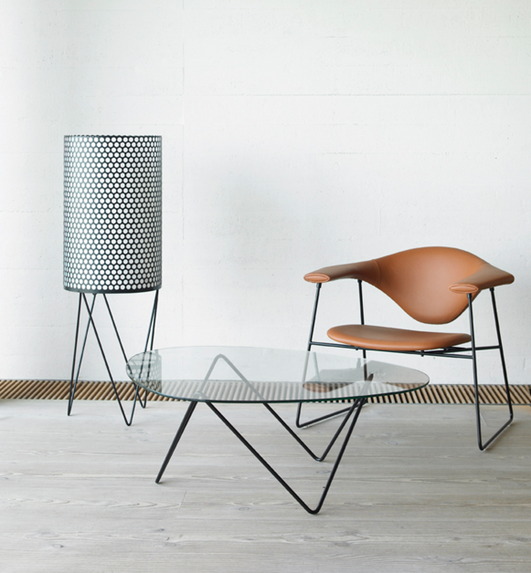 Pedrera Stehleuchte von Gubi, Design-Lampe mit gelochtem Schirm, kombiniert mit Sessel und Glastisch.