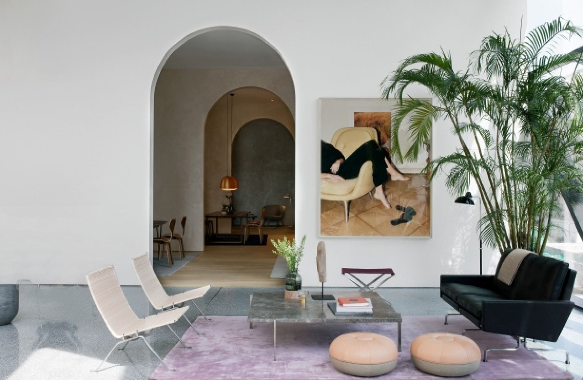 Helles Wohnzimmer mit schwarzem PK 31 Sofa von Fritz Hansen, lila Teppich und Kunst.