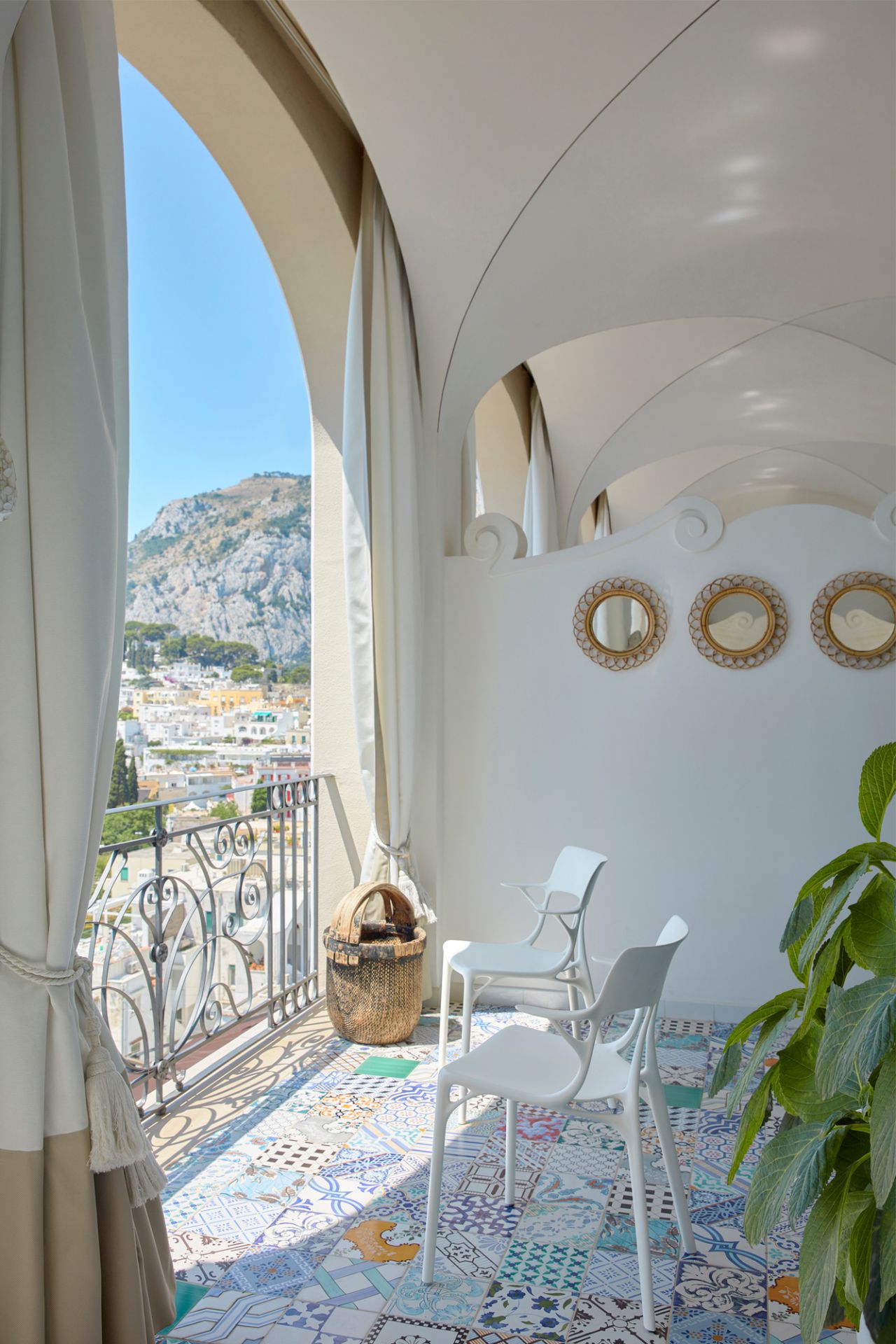 Zwei weiße A.I. Stühle von Kartell auf einem Balkon mit Blick auf eine Stadt.