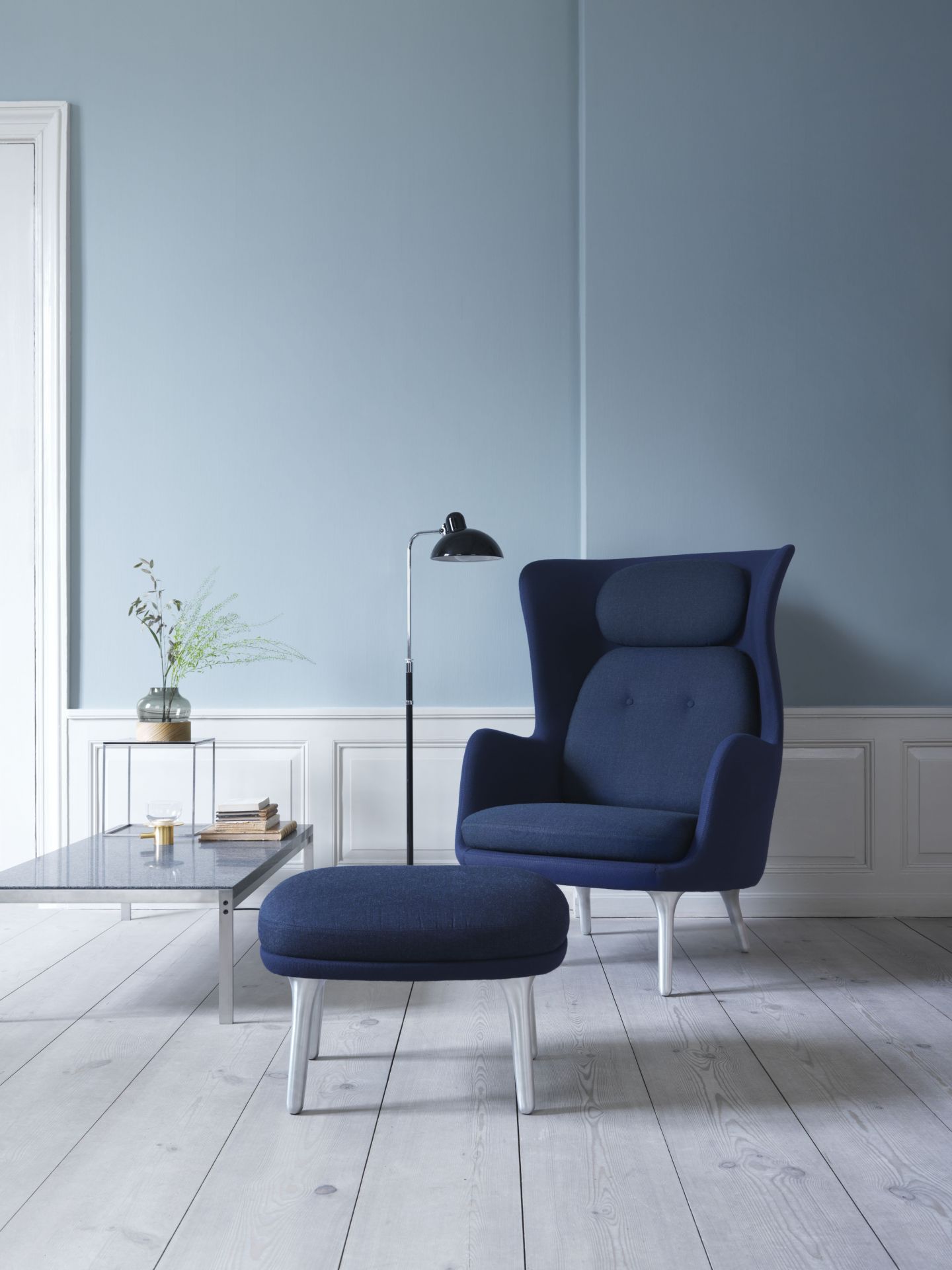 Blauer Ro Sessel von Fritz Hansen mit Aluminiumfuß und passendem Hocker im Wohnzimmer.