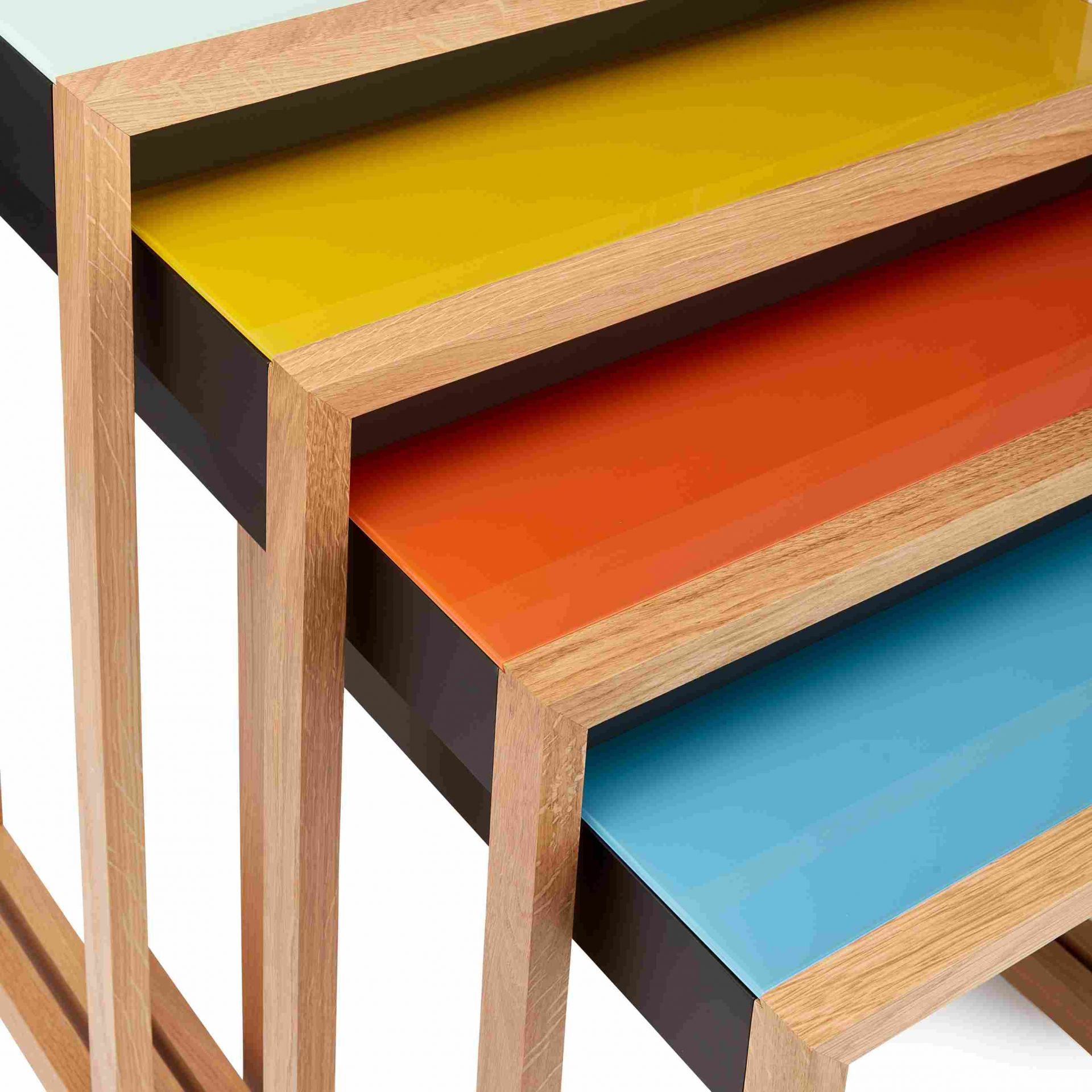 Bauhaus Satztische 4er Set von Klein & More mit farbigen Tischplatten aus Glas und Holzrahmen.