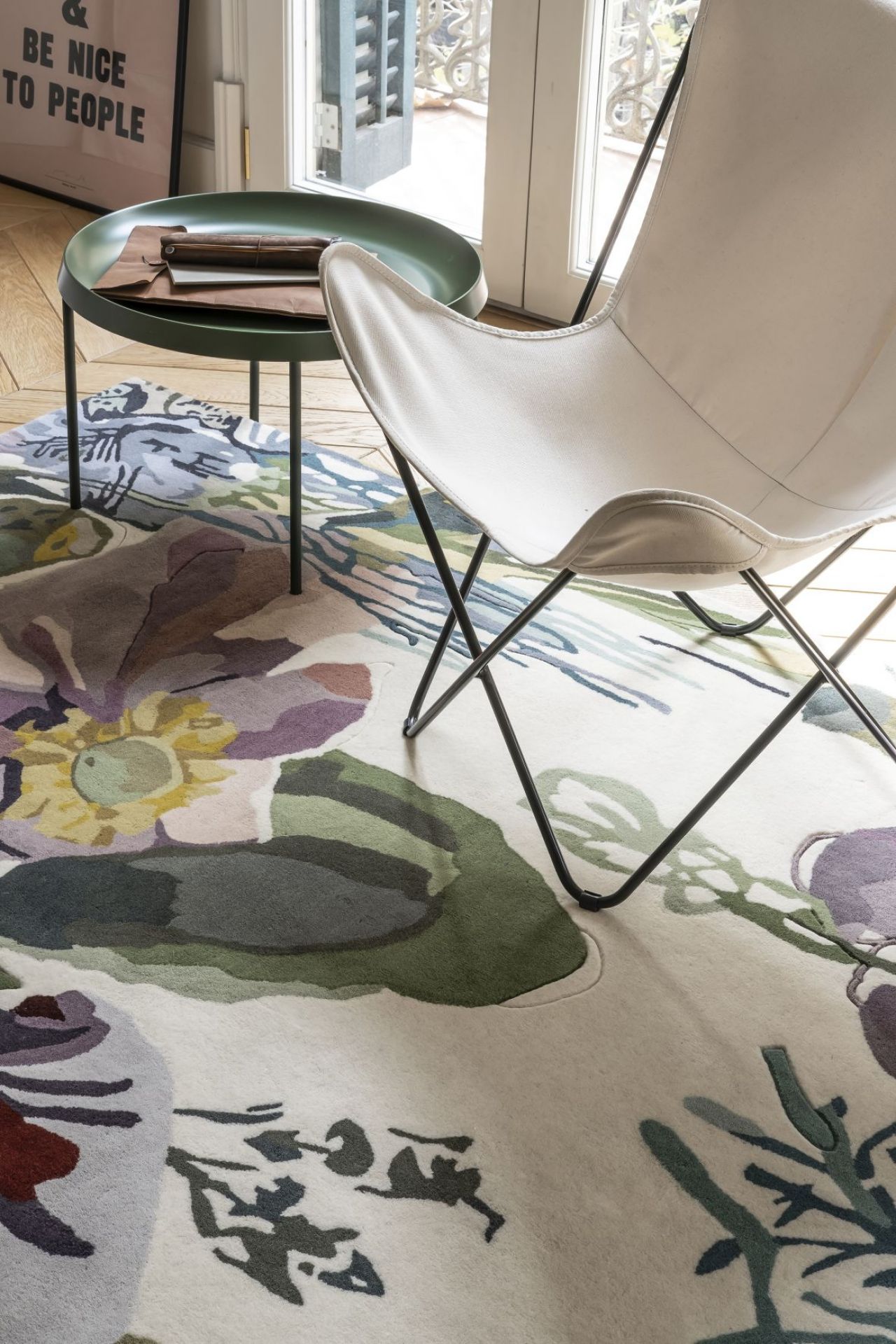 Detailaufnahme des Nanimarquina Flora Backyard Teppichs mit floralem Muster, Stuhl und Beistelltisch.