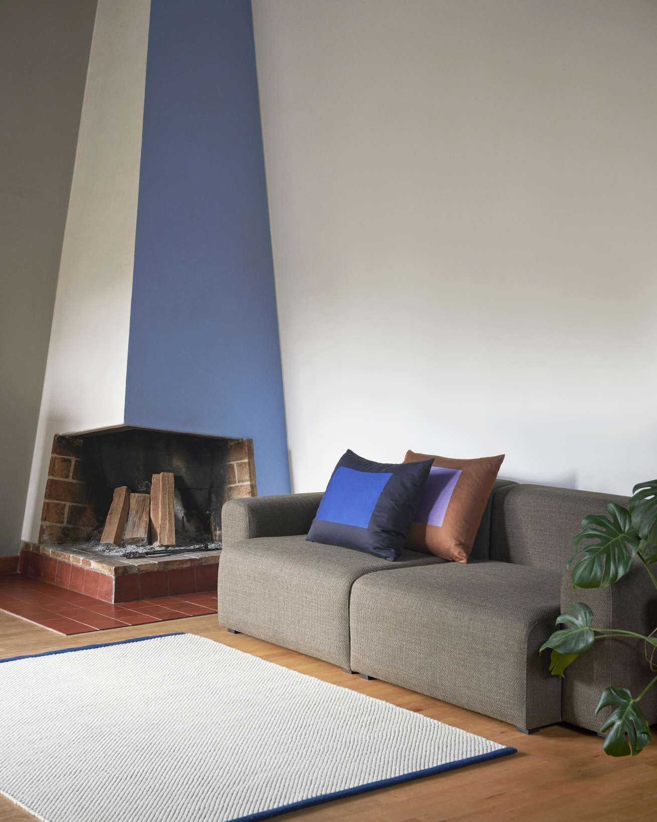 Hay Bias Rug Tint Teppich in Schwarz-Weiß mit blauem Rand im Wohnzimmer.