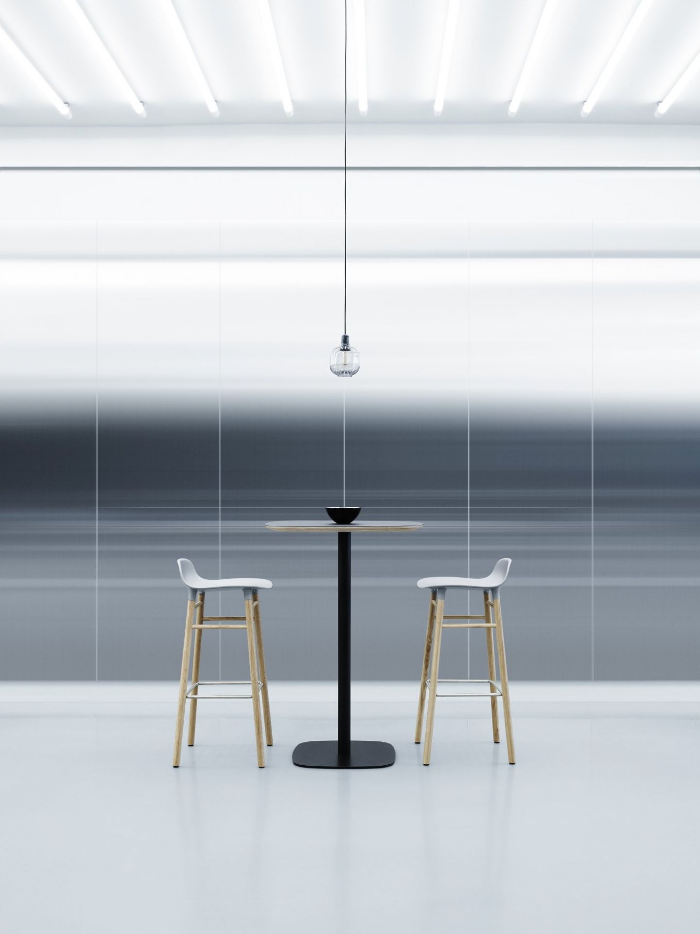 Zwei Form Barhocker H 75 cm von Normann Copenhagen an einem Stehtisch in minimalistischem Ambiente.