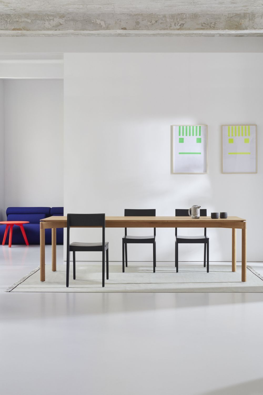 WEDEKIND Esstisch aus Eiche, gewachst, in Large Ausführung mit schwarzen Stühlen in minimalistischem Interieur.