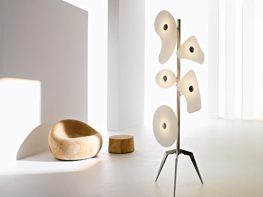Moderne Stehlampe mit abstrakten Formen und Holzmöbeln in minimalistischem, hellem Interieur.