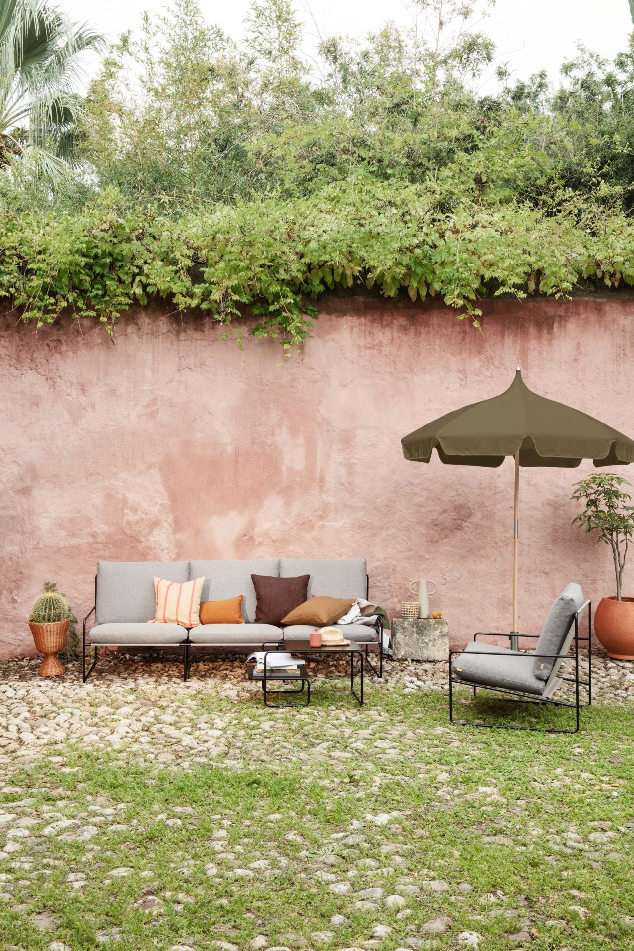 Desert Sessel: Ferm Living Outdoor Sessel mit Cashmere-farbenem Bezug und schwarzem Gestell im Garten.