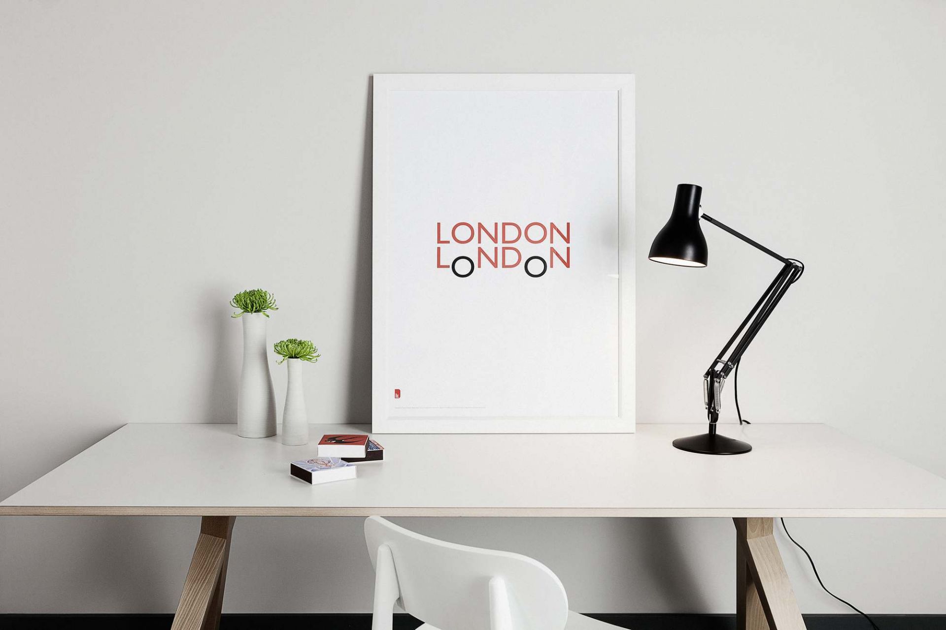 Schwarze Anglepoise Type 75 Schreibtischlampe auf weißem Schreibtisch mit London-Poster, ideal für modernes Arbeitszimmer.