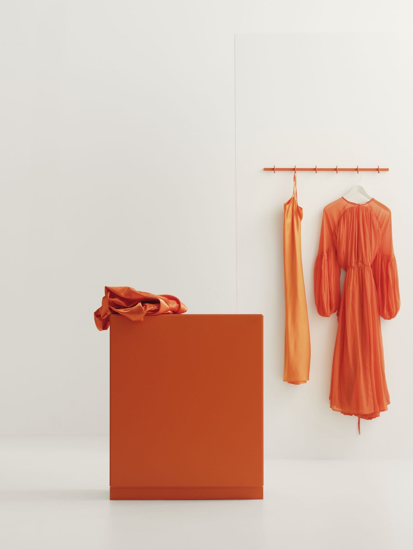 Graue Relief Hakenleiste B82cm von String Furniture an einer Wand mit Kleidung.