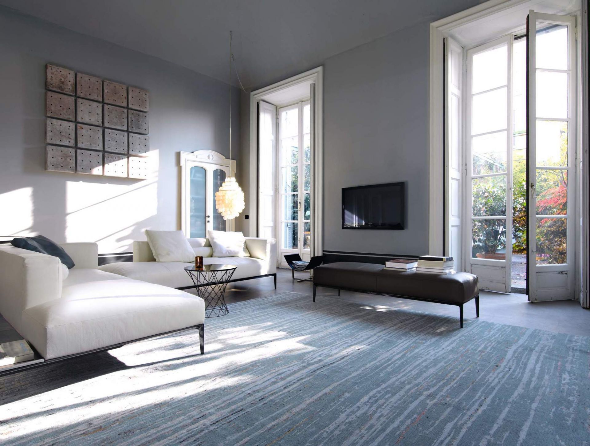 Helles Wohnzimmer mit weißer Jaan Living Polsterbank und brauner Lederbank von Walter Knoll.