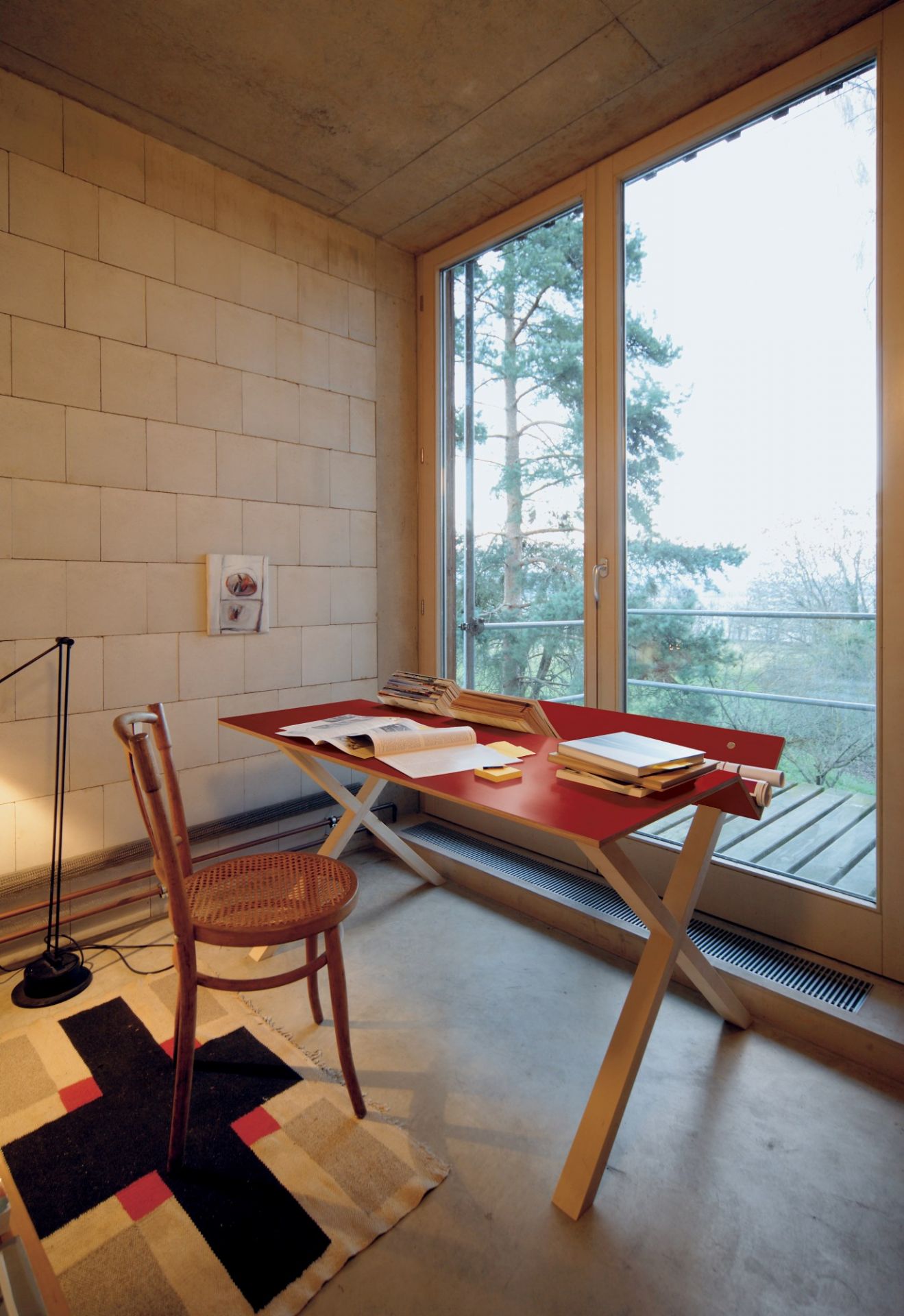 Roter Kant Schreibtisch von Nils Holger Moormann in minimalistischem Raum mit Stuhl und Teppich.
