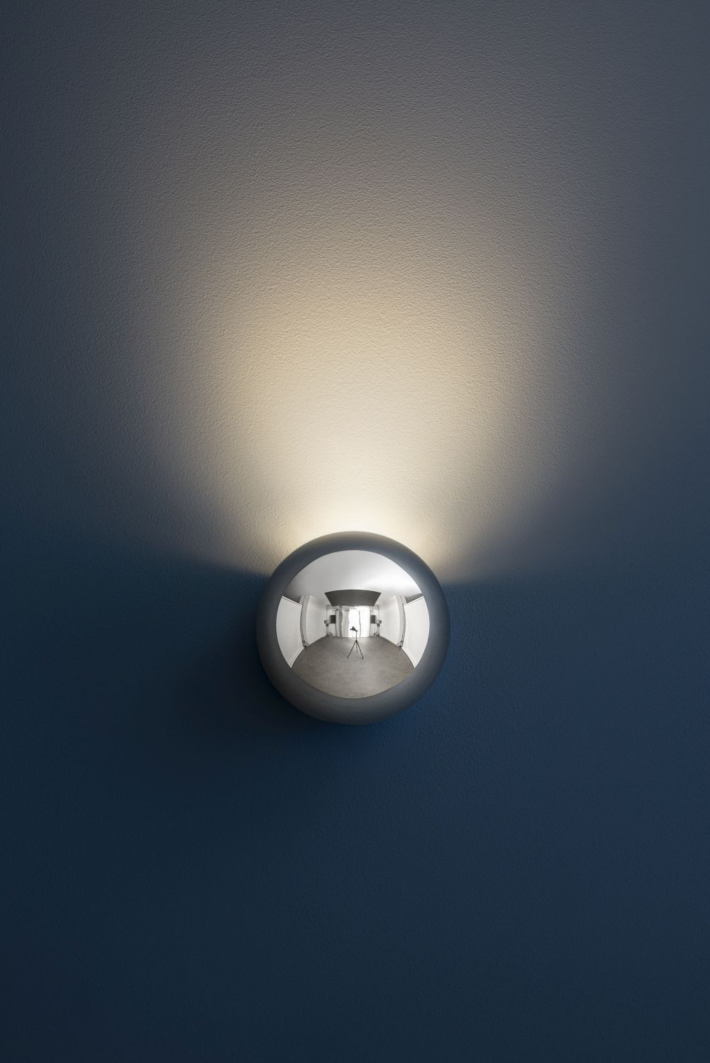 Sfera Wandleuchte von Catellani & Smith: Runde, silberne Designleuchte an blauer Wand. Indirekte Beleuchtung.