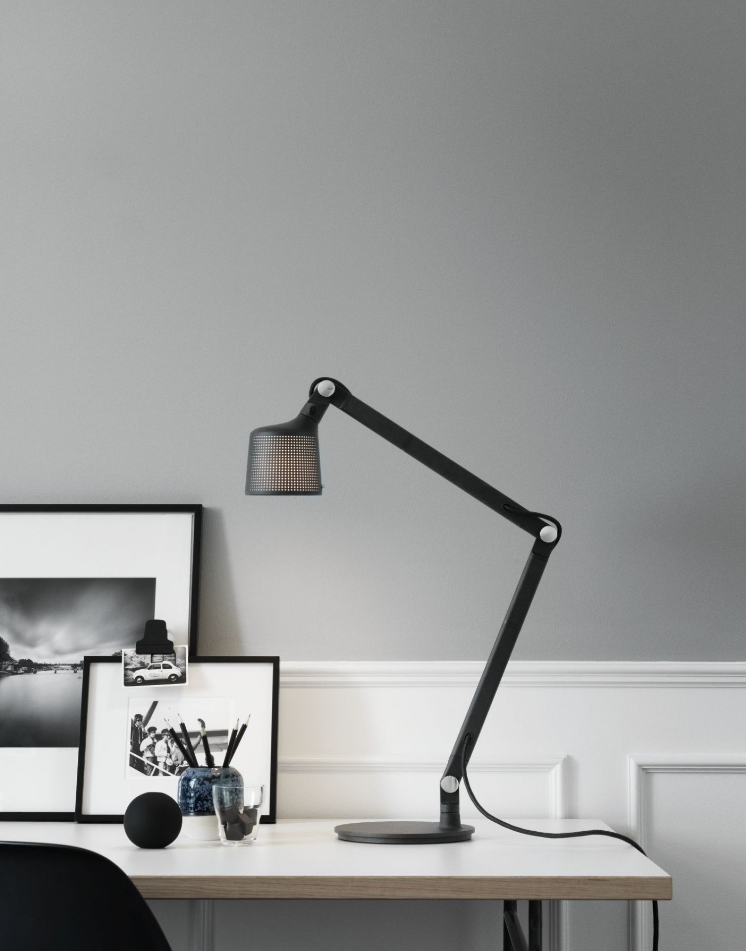 Schwarze Vipp Tischleuchte auf einem Schreibtisch mit minimalistischer Dekoration, ideal als Arbeitsleuchte und Designelement.