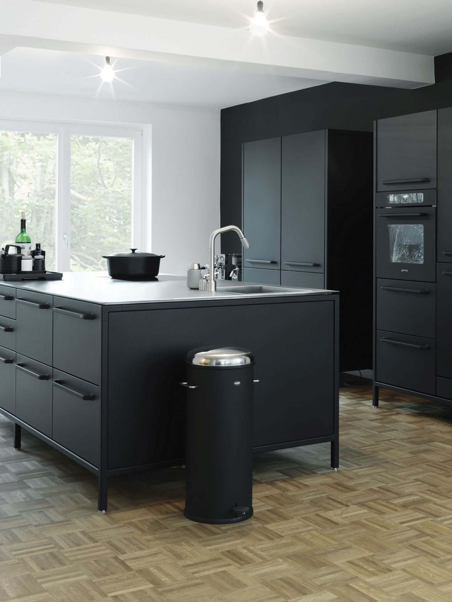 Schwarzer Vipp Treteimer 30L in moderner Küche mit dunklen Schränken und hellem Holzboden. Design Mülleimer mit Fußpedal.