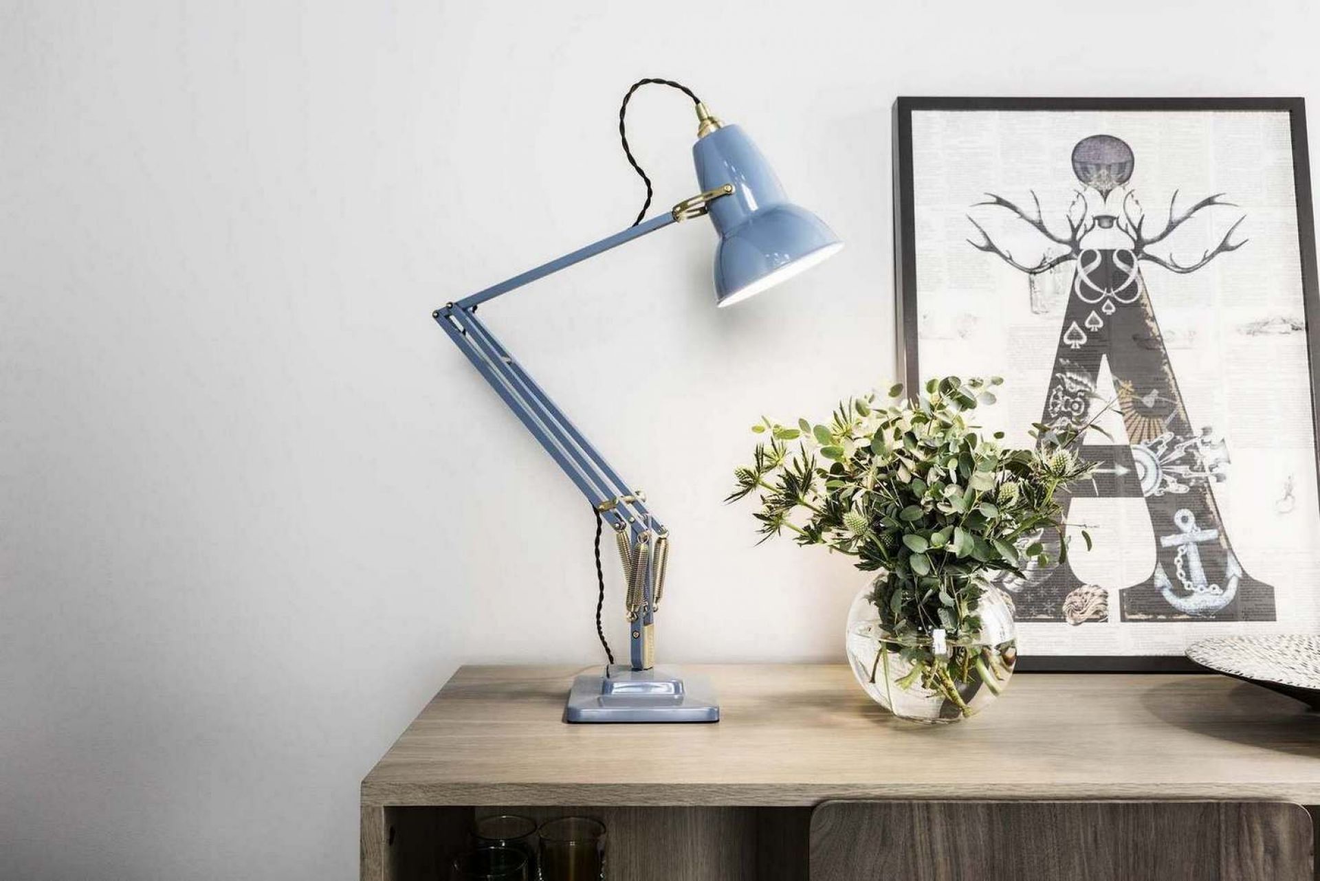 Original 1227 Anglepoise Tischleuchte aus Messing in Taubengrau auf einem Holztisch mit Dekoration.