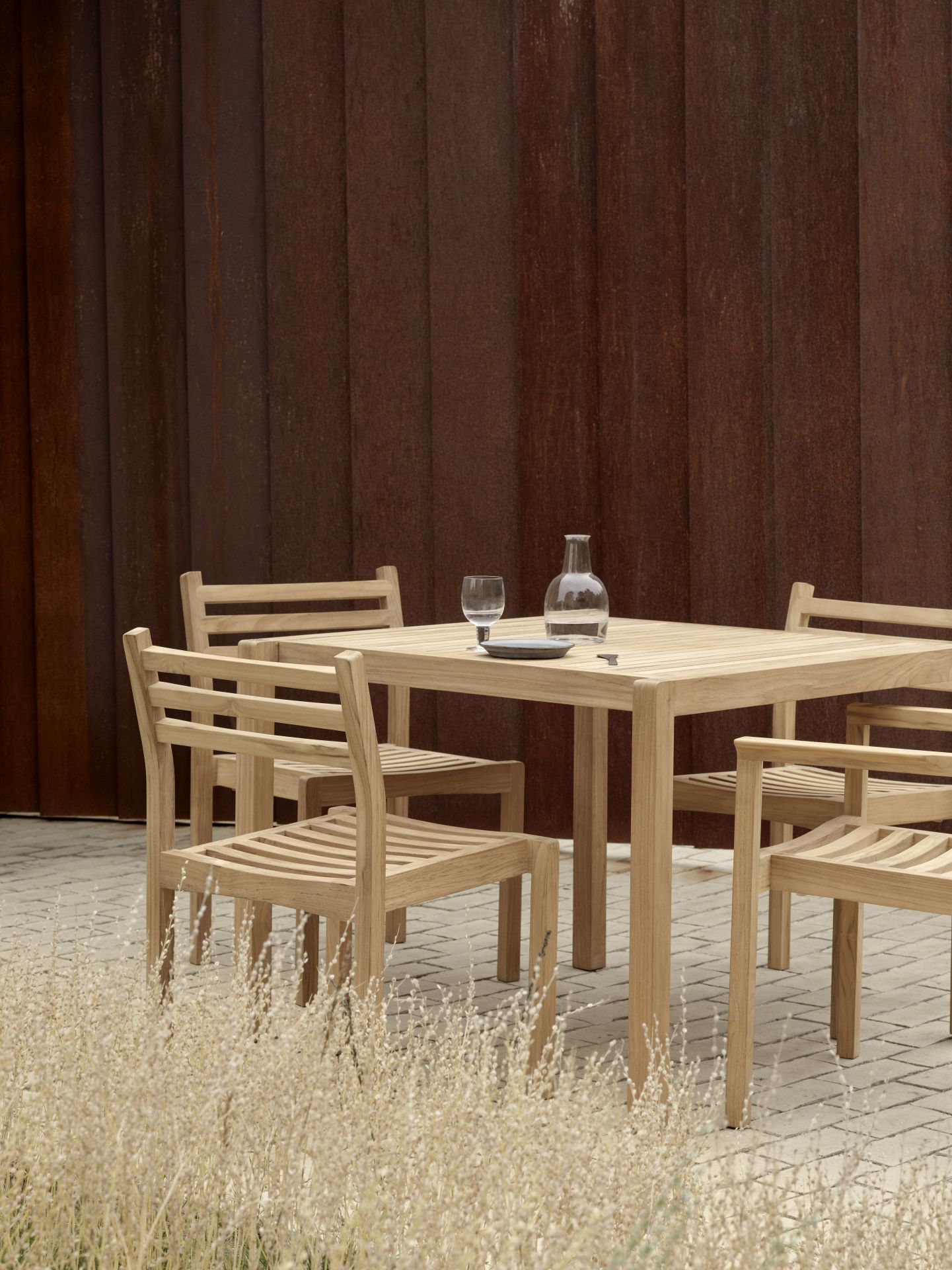 AH902 Carl Hansen Esstisch Outdoor mit vier Stühlen aus Teakholz und Glasflasche.