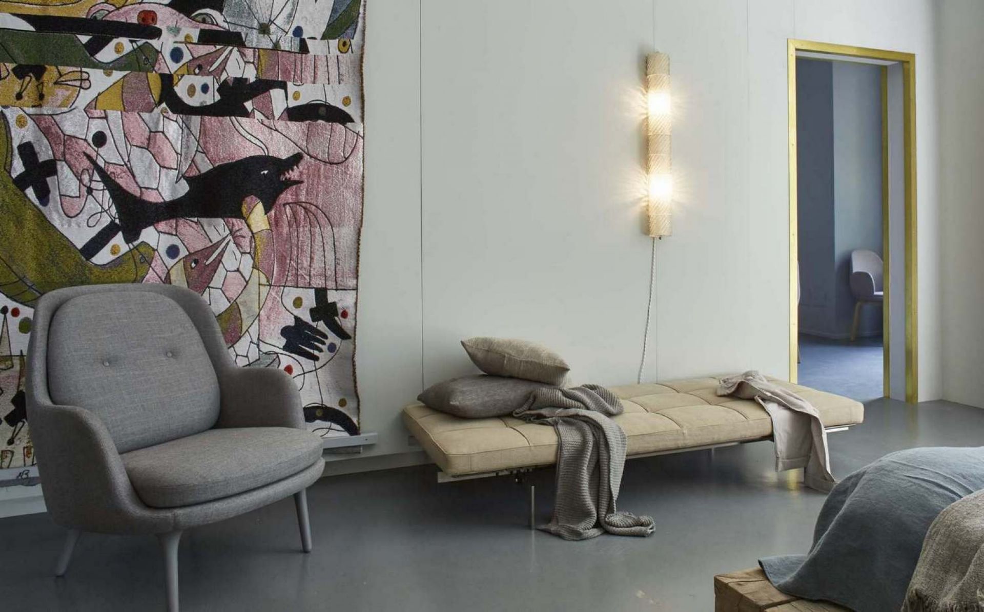 Grauer Fri Sessel von Fritz Hansen in modernem Wohnzimmer mit Tagesbett und Wandteppich.