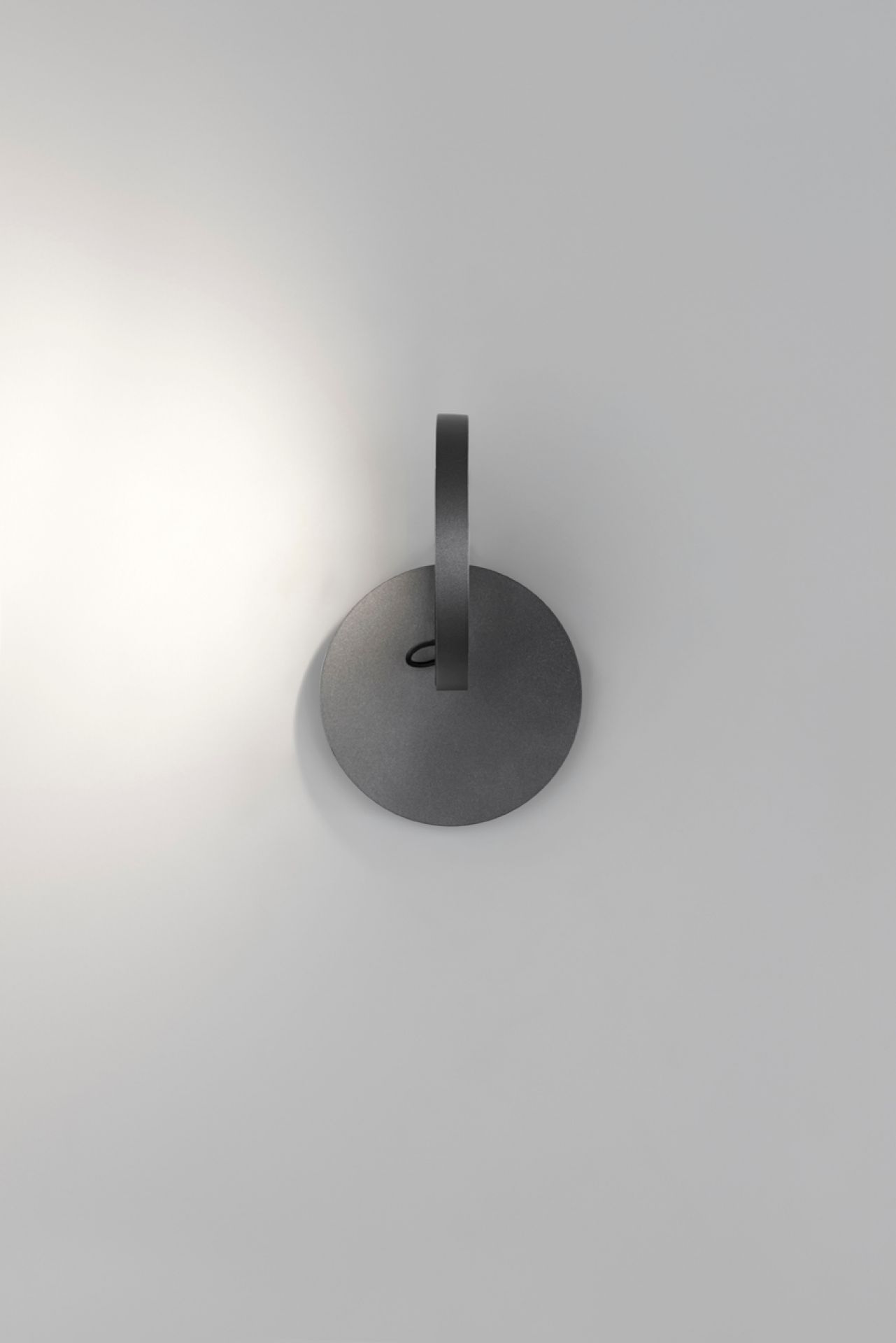 Nahaufnahme der grauen Demetra Faretto Wandleuchte von Artemide mit Schalter an einer weißen Wand.
