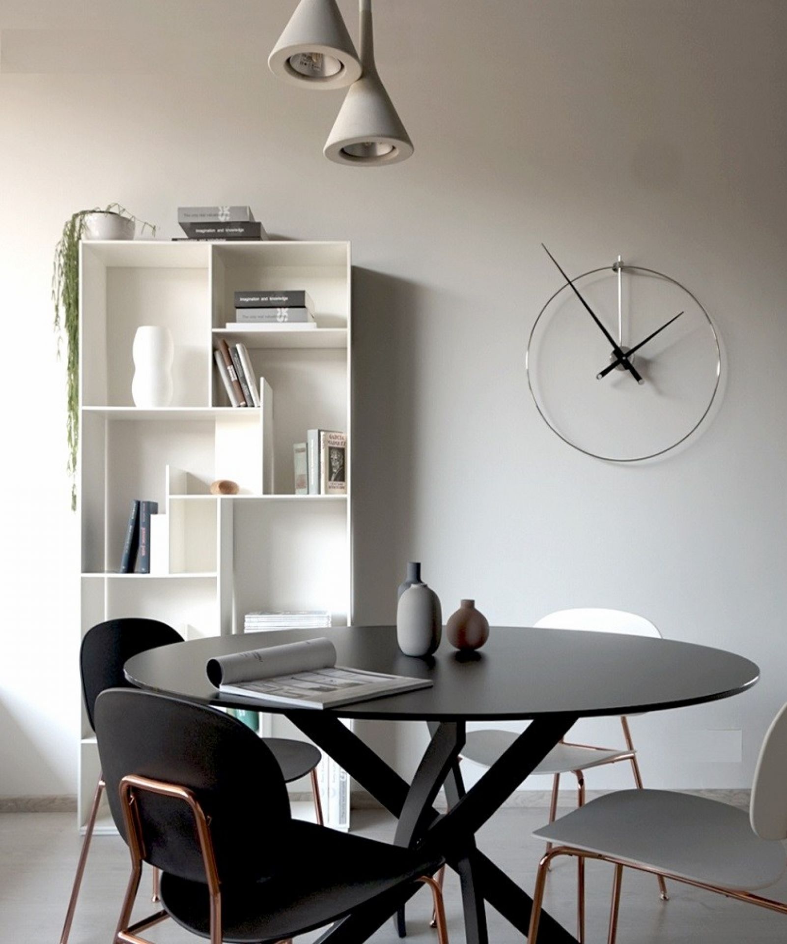 Helle Inneneinrichtung mit Esstisch, Stühlen, Bücherregal und einer runden New Anda Clock Wanduhr von Nomon.