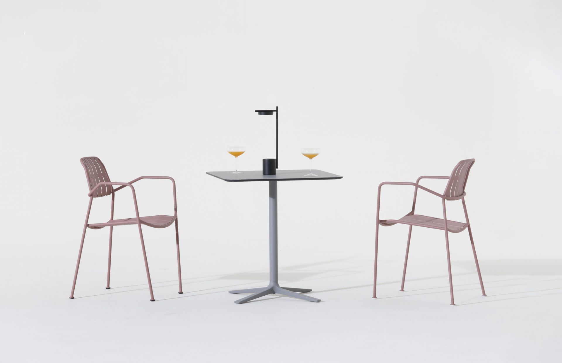 Osmo Outdoor Stuhl Teak Prostoria, rosafarbene Gartenstühle mit Armlehne und Tisch mit Getränken auf weißem Hintergrund.