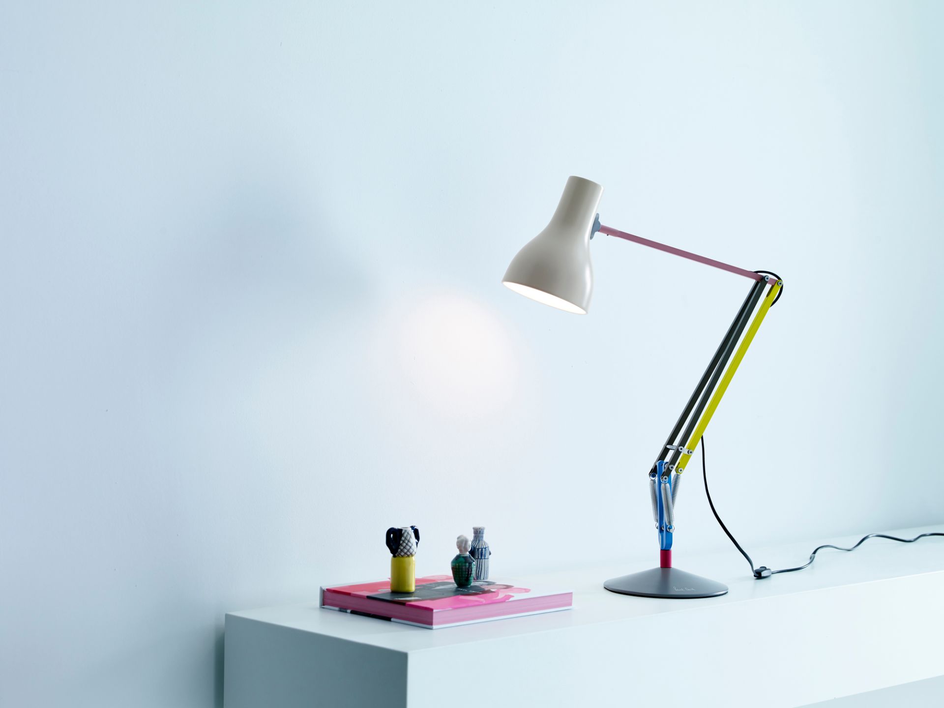 Anglepoise Type 75 Mini Paul Smith Edition 1 Tischleuchte in Beige mit farbigen Akzenten auf weißem Tisch.