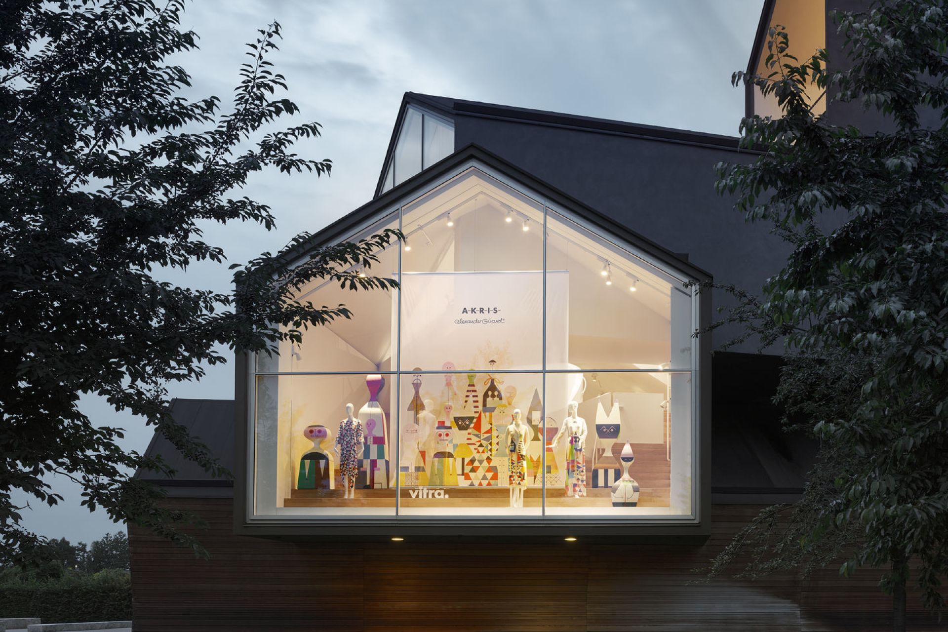 Schaufenster mit Vitra Wooden Dolls Holzfiguren und Akris Modekollektion, bunte Designobjekte und Kleidung auf Schaufensterpuppen.
