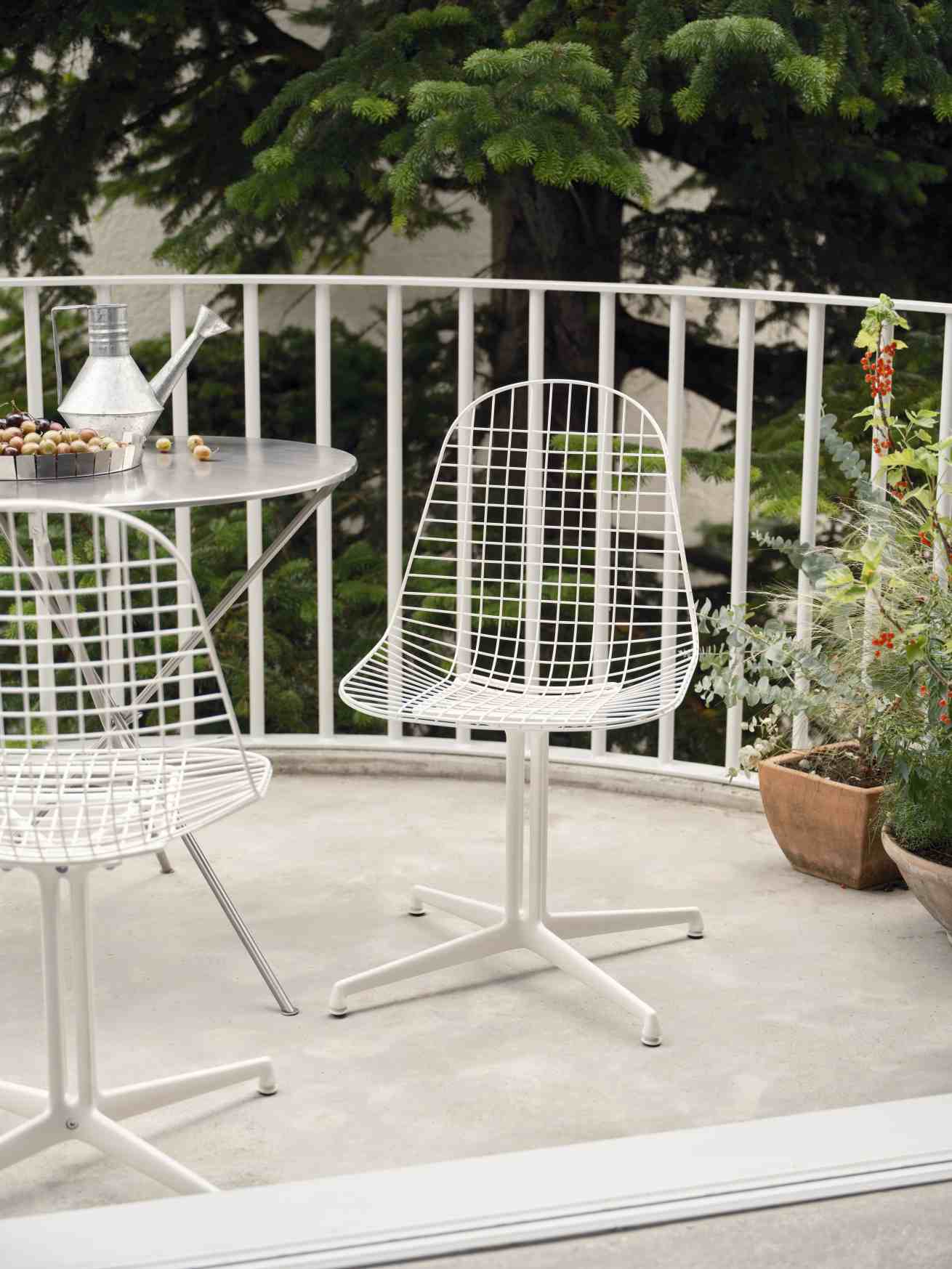 Weißer DKL Wire Chair Stuhl von Vitra, ungepolstert, auf einer Terrasse mit Tisch und Pflanzen.