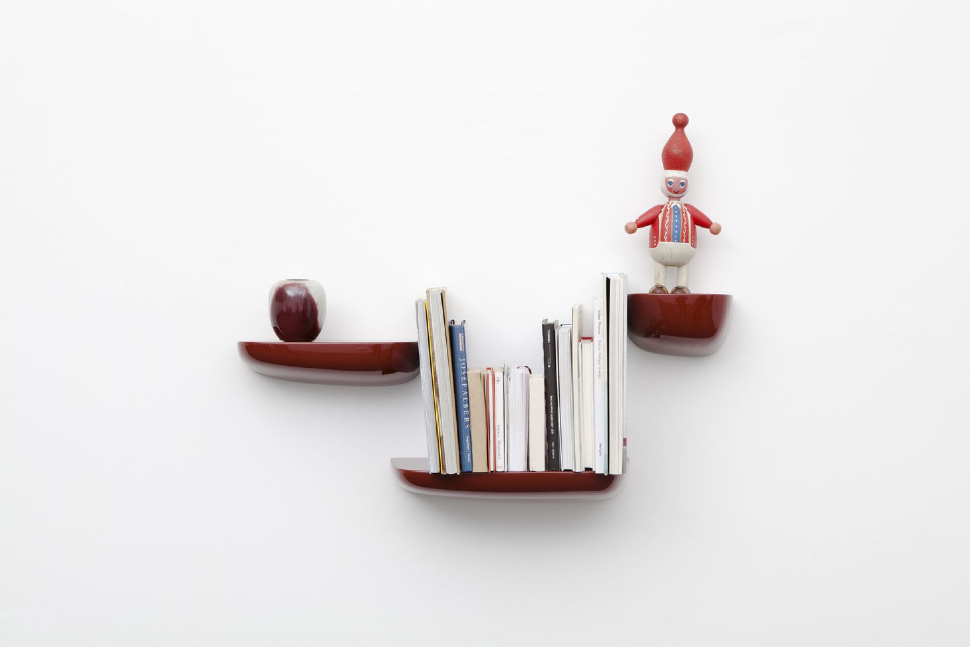 Rote Corniches Wandboards von Vitra an weißer Wand mit Büchern, Vase und Holzfigur.