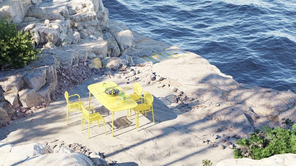 Gelber Week-End Gartenstuhl mit Armlehnen von Petite Friture auf felsiger Terrasse am Meer.