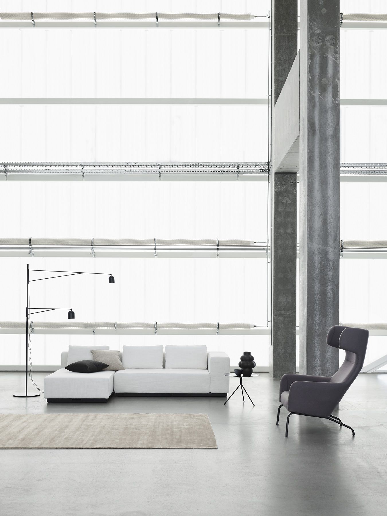 Moderner grauer Havana Armchair Ohrensessel von Softline neben weißem Sofa und Beistelltisch in Loft.